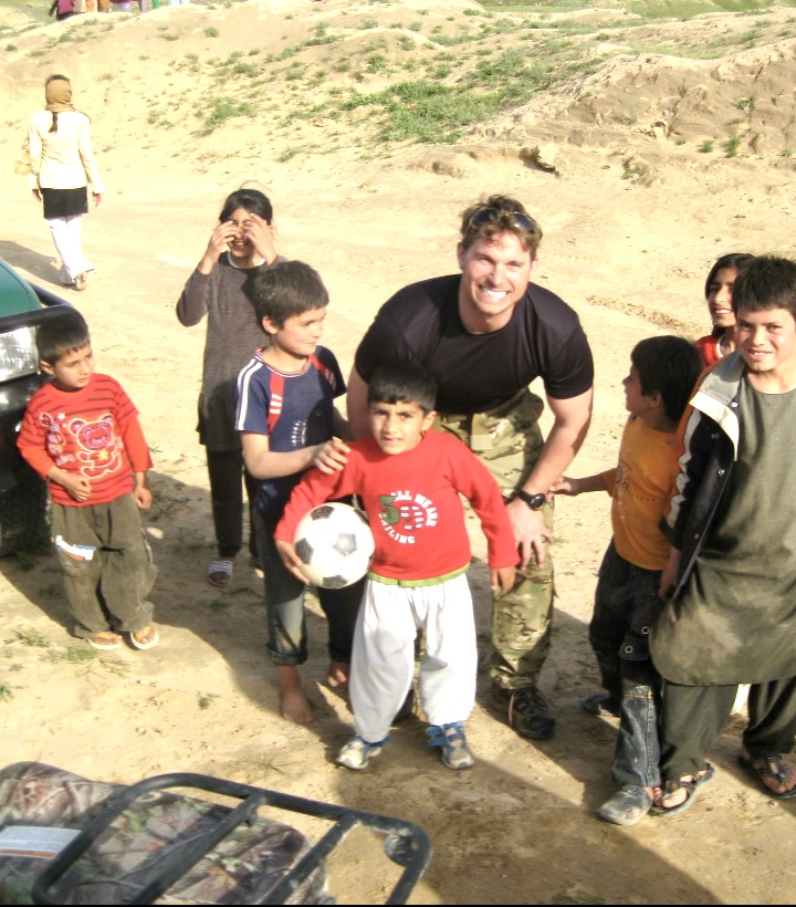 John Siver II with local children and a soccer ball overseas